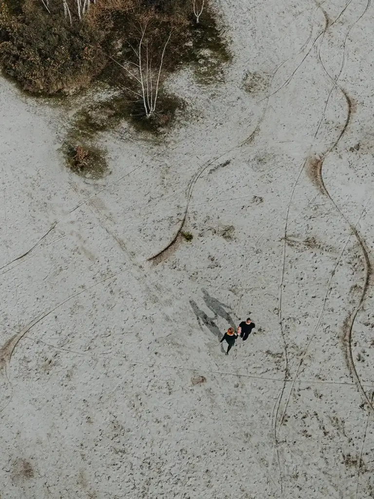 Das verliebte Paar läuft durch den Sand fotografiert von oben mit einer Drohne