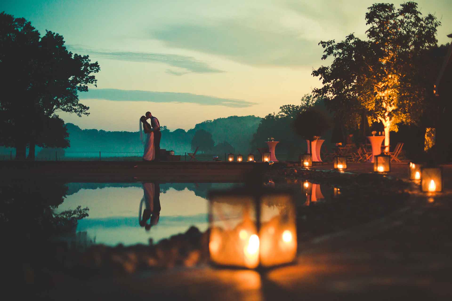 Das Brautpaar steht an einem See im Sonnenuntergang. Fotografiert an der Hochzeitslocation in Leipzig