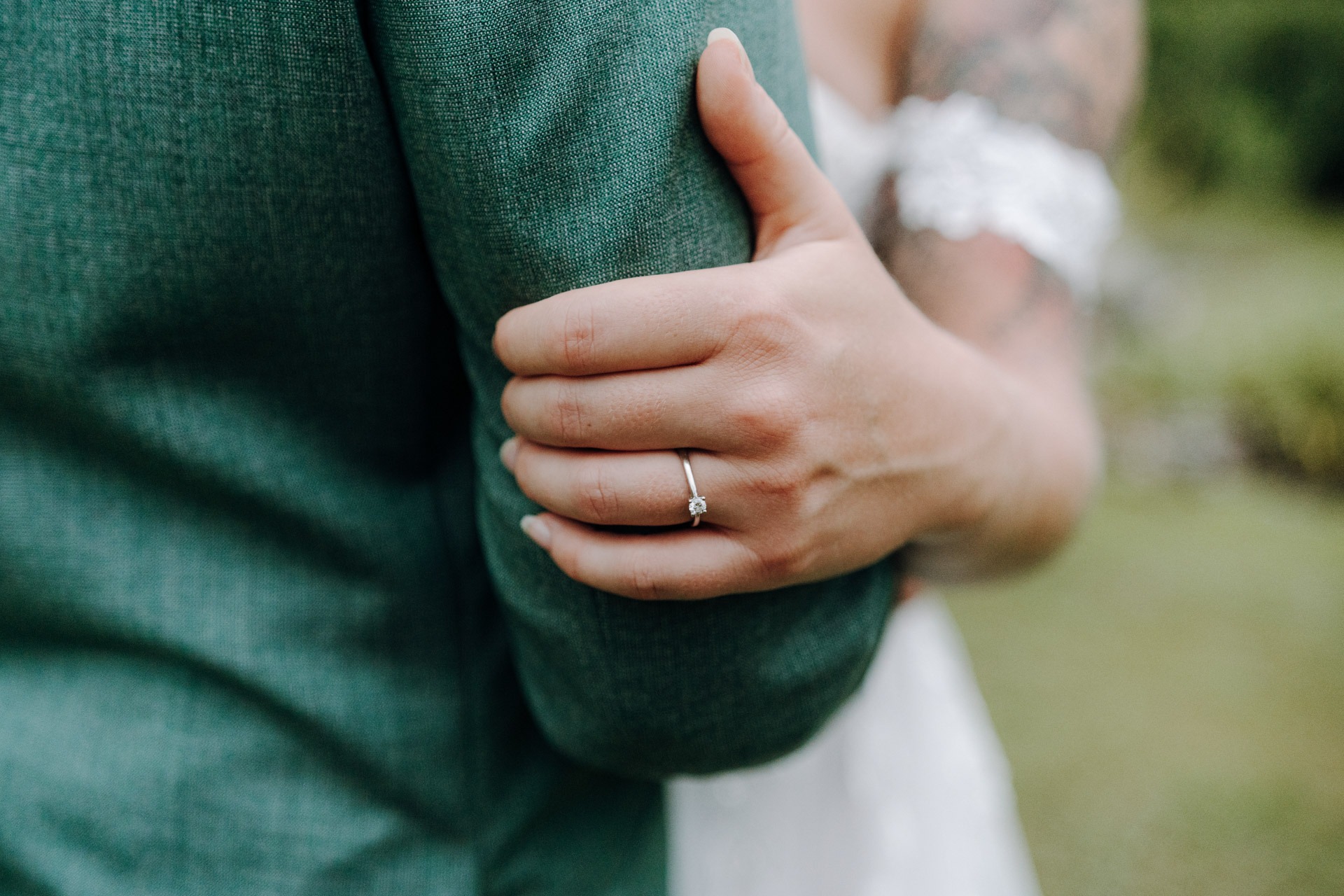 Detail der Hand der Braut am Anzug des Bräutigams als liebevolles Hochzeitsdetail