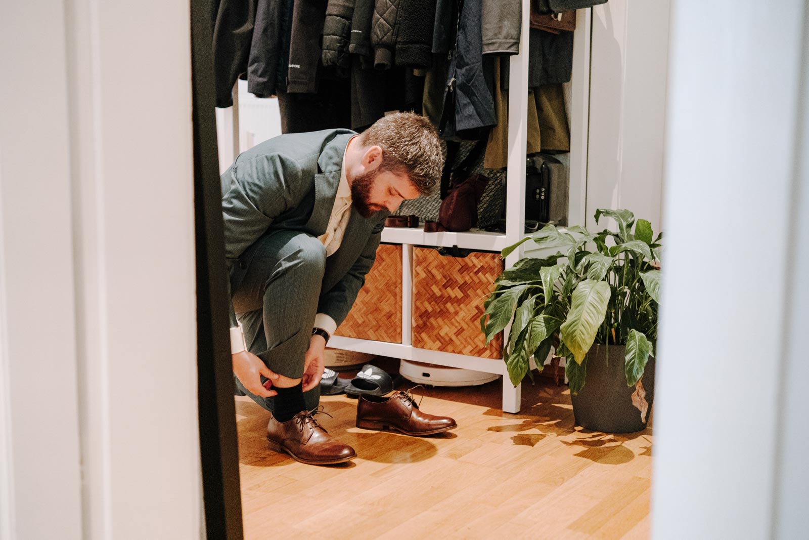 Jonas beugt sich in der Wohnung nach unten, um seine braunen Schuhe anzuziehen.