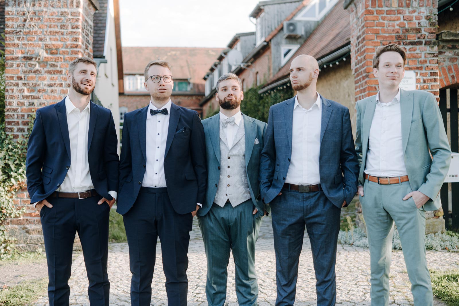 Jonas und vier Freunde stehen vor Backsteinwänden zusammen und lachen miteinander.